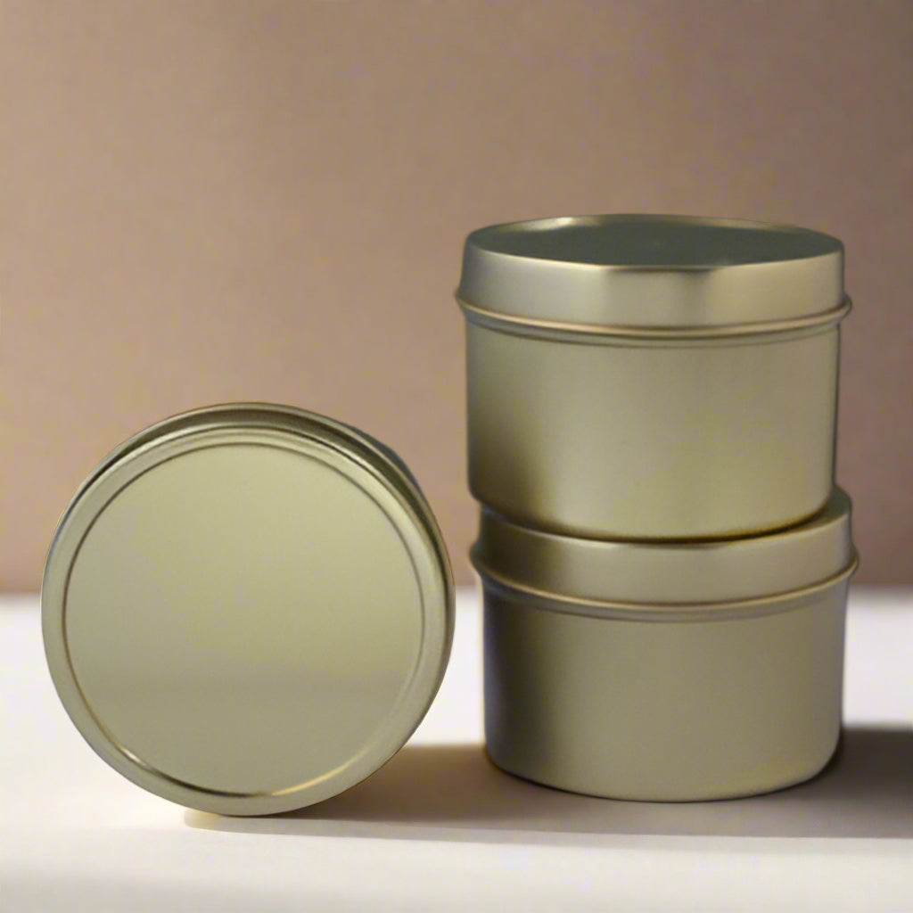 Two gold metal tins with lids on a purple and gray gradient background